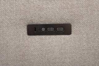 Black rectangular switch panel with buttons on a beige fabric sofa