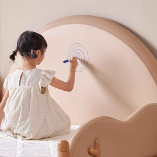 Child drawing on a round, beige wall with a marker