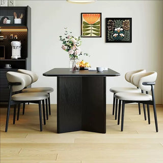 Dining room with a black table and white chairs, featuring a vase of flowers and decorative items.
