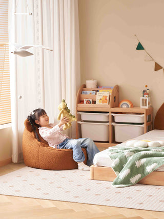 Child playing with a toy in a cozy bedroom with a bed and storage unit.