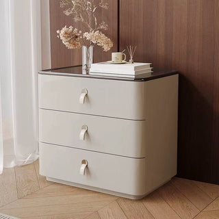 3 drawer bedside table with black top against a wooden wall