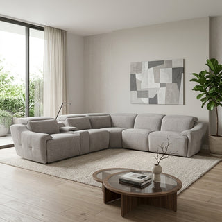 A light grey sectional recliner sofa in a modern, sunlit living room with a beige rug, wooden coffee table, and abstract wall art.