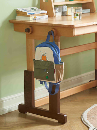 Backpack hanging on a wooden stand with a desk in the background