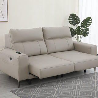 Beige extendable sofa in a living room setting with a plant and rug.