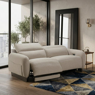 Beige recliner sofa in a modern living room with large windows and decorative rug.