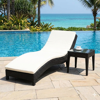 Black wicker lounge chair with white cushion next to a pool with ocean view