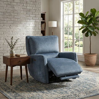 Blue recliner chair in a living room with a brick wall, side table, and large window.