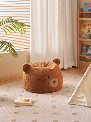 Brown bear-shaped kids bean bag chairs in a room with books and a plant