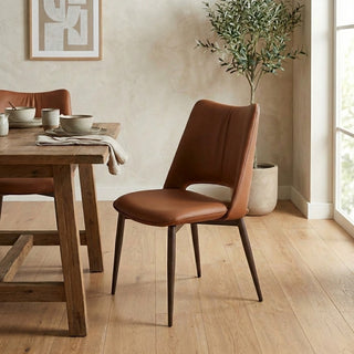 Brown leather chair in a dining room setting with a wooden table and decor.