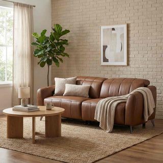 Brown leather sofa in a living room with a coffee table, plant, and wall art.