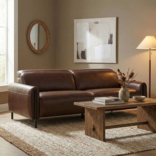 Brown leather sofa in a living room with a wooden coffee table and decorative items.