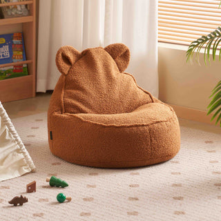 Brown teddy bear-shaped bean bag chair in a room with toys on the floor.