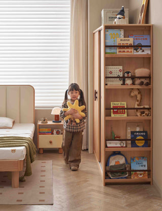 Child holding a star-shaped toy in a bedroom with a bookshelf and bed.