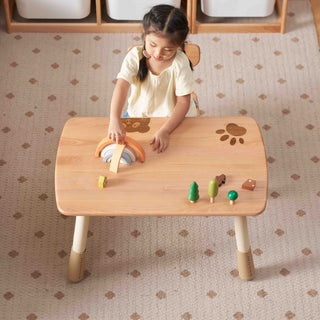 Child playing with toys on a wooden table in a room with patterned carpet.