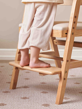 Child's feet on a wooden step stool with a chair in the background