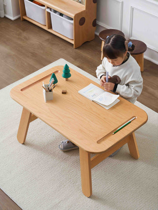 Child sitting at a small childrens activity table in a room with storage shelves.