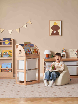 Child sitting on a bean bag chair in a playroom with bookshelves and a desk.