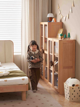 Child standing in a room with wooden furniture and toys