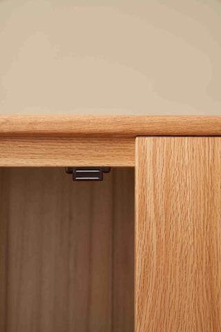 Close-up of a wooden cabinet with a visible hinge on a beige background