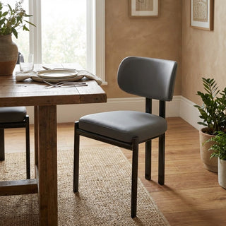 Dining chair with gray cushion in a room with a wooden table and plants.