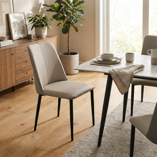 Dining room with a beige chair, table, and potted plants.