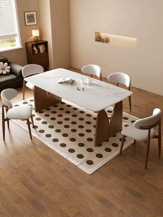 Dining room with a marble table and white chairs on a polka dot rug.