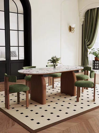 Dining room with a modern oval table and green chairs on a patterned rug.