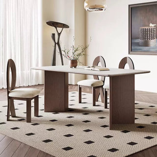 Dining room with a modern table and chairs on a patterned rug.