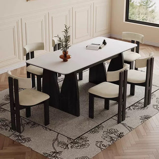 Dining room with a white table and black chairs on a patterned rug.