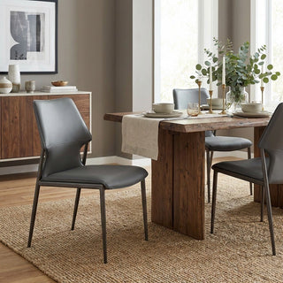 Dining room with wooden table and gray chairs, featuring a rug and decor.