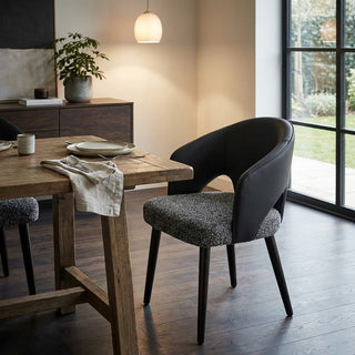 Dining room with wooden table and modern chairs near a window.