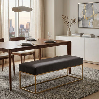 Dining room with wooden table, chairs, and a grey bench with gold legs.