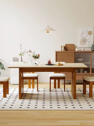 Dining room with wooden table, chairs, and decor in a modern interior setting.