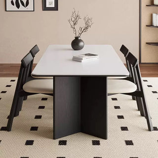 Dining table with chairs in a room with a patterned rug and neutral walls.