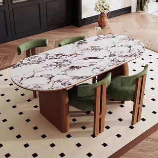 Dining table with marble-like top and wooden legs in a room with green chairs and a patterned rug.