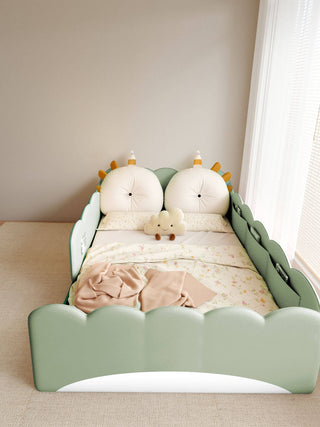Children's bed with green headboard and white mattress in a room with light-colored walls and a window.