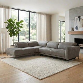 Gray sectional sofa in a modern living room with large windows and a fireplace.