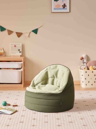 Green bean bag chair in a child's room with toys and storage bins.