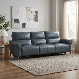 Grey leather sofa in a living room with a rug, table, and artwork on the wall.