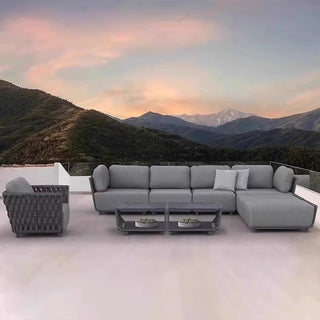 Grey outdoor sectional sofa with a matching armchair on a rooftop with mountainous landscape and rainbow.