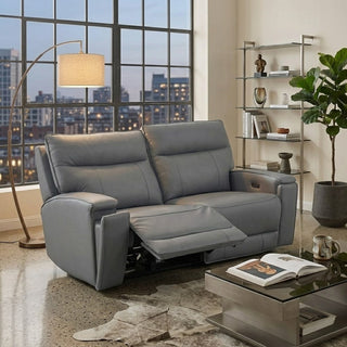 Grey recliner sofa in a living room with a cityscape view through large windows.