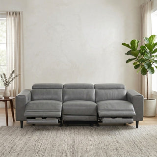 Grey sectional recliner sofa in a living room with a plant and small table.
