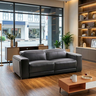 Grey sofa in a modern living room with wooden floor and large windows.