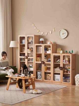 Living room with wooden bookshelves, a child sitting on a small table, and a woman reading.