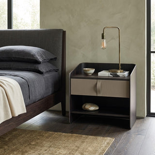 Modern bedroom with a bed and designer bedside table featuring a lamp and small items.