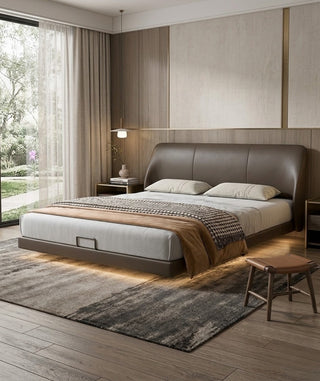 Modern bedroom with a leather bed, wooden floor, and large window.