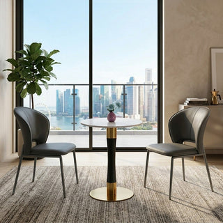 Modern dining area with a round pedestal table and chairs in a room with large windows overlooking a cityscape.