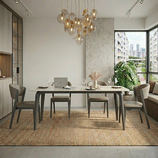 Modern dining area with a sintered stone dining table, chairs, and a laptop in a well-lit room.