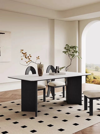 Modern dining room with a black and white table and chairs on a patterned rug.