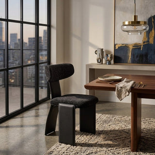 Modern dining room with a black chair, wooden table, and abstract art on the wall.
